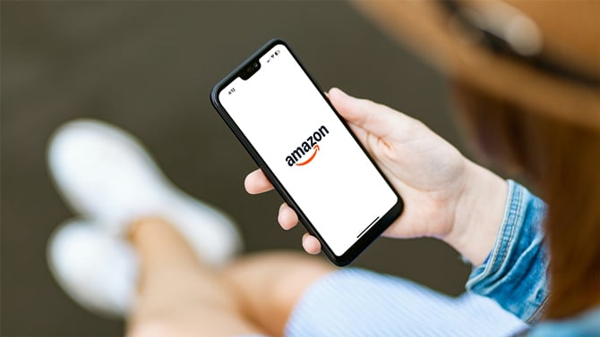 Phone shows the Amazon app startup screen with the Amazon smile logo