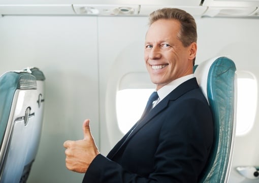 Businessman giving thumbs up on airliner