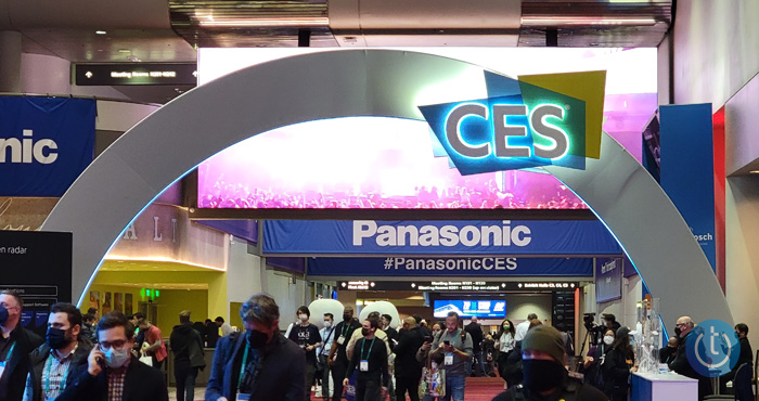 Shot of the entrance to the Las Vegas Convention Center showing the CES logo on an arch and masked people walking underneath