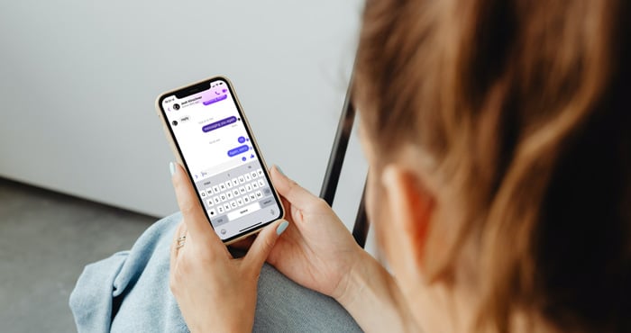 Woman holding iPhone showing a conversation on the Facebook Messenger app