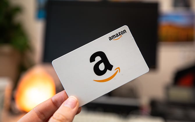 Hand holding an Amazon gift card with the Amazon smile logo.