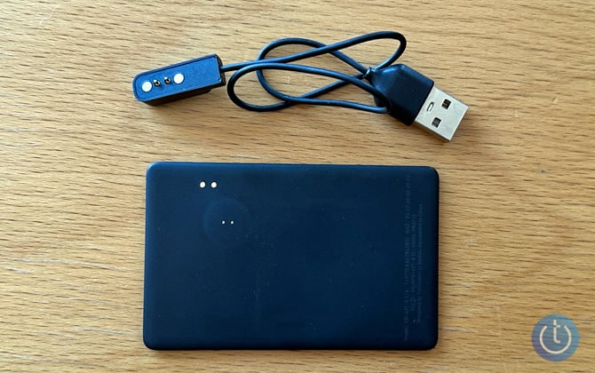 The back of the Pebblebee card is shown on a wooden deck with a USB-A charger.