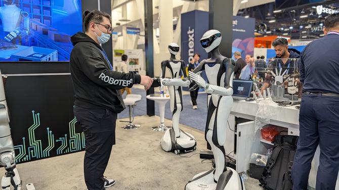 Man shaking a robots hand in CES booth