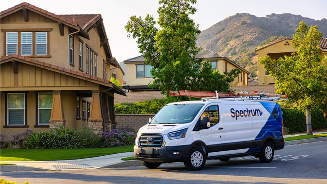 A Spectrum van parks in front of a home.