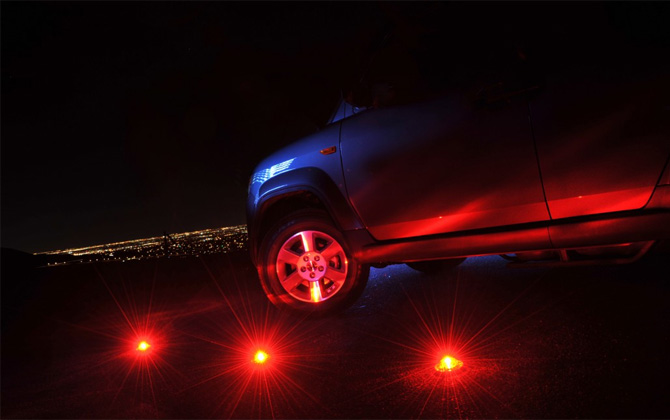 Stonepoint Emergency Roadside Beacons set on the road near the front tire of a car at night.