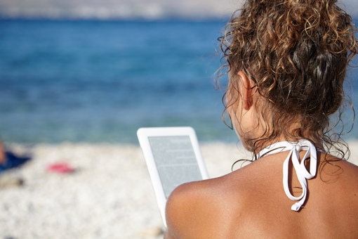 Woman on beach with e-reader