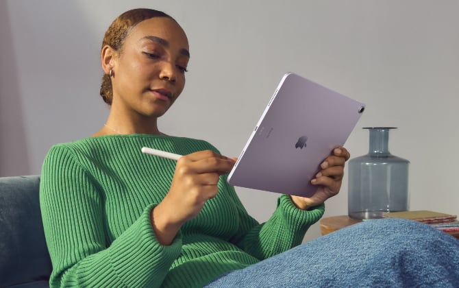A woman in a chair drawing on an iPad with an Apple Pencil