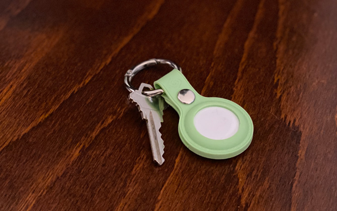 Apple AirTag in Grip2U green keyring on wood surface