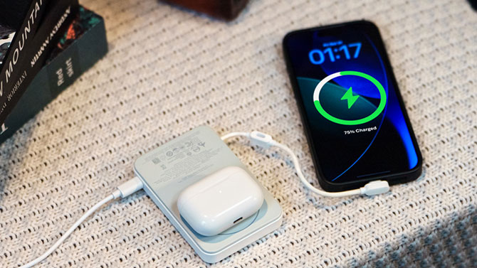 An EcoFlow Rapid Mag Qi2.2 power bank sits on a table wirelessly charging headphones and wired charging an iPhone