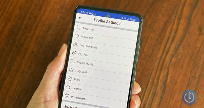 Phone held in hand showing the Facebook Profile Settings page you see when you click on the triple dots in the upper right of their profile page.