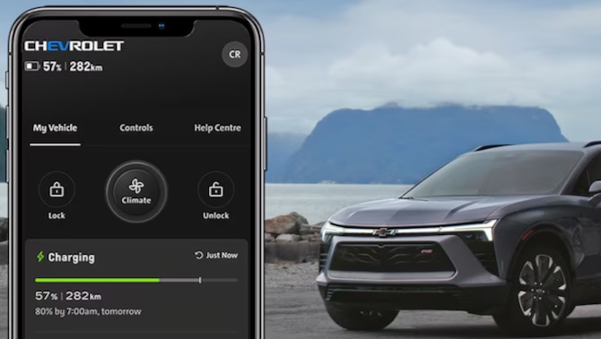 Photo of GM Onstar mobile app on a phone in the left forground and a GM car in the right background