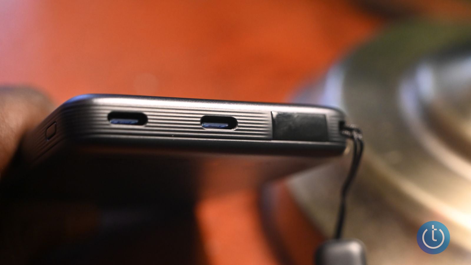 Close-up of the INIU SnapGo Air's pair of USB-C ports and status button along the bank's edge, with the integrated cable loop visible.