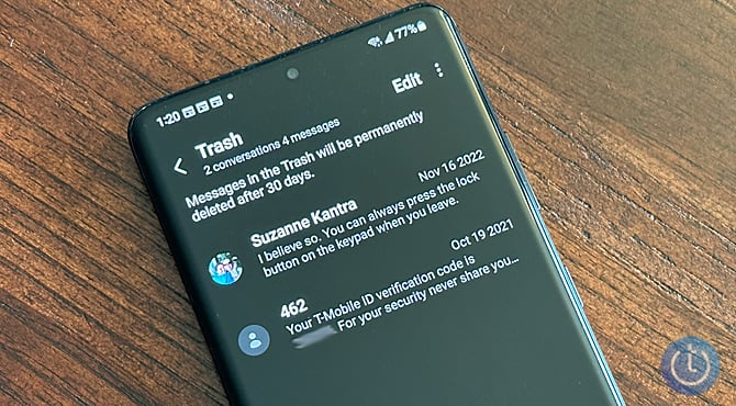Samsung Galaxy S22 on wood table showing the Trash folder in the messages app.