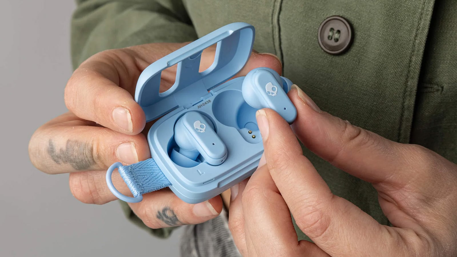 Skullcandy Dime 3 wireless earbuds in blue, shown with their open charging case in a person's hands.