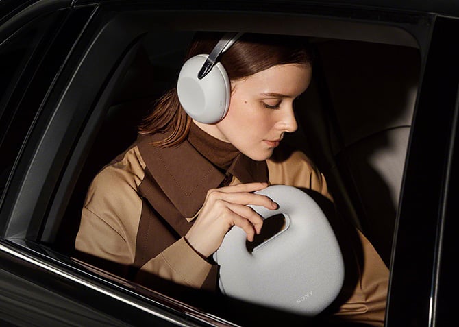 The Sony 1000X The Collection headphones in platinum worn and shown with carry case.