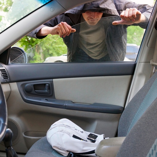 Thief stealing a phone from a parked car